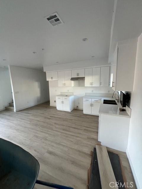 kitchen with sink, light hardwood / wood-style flooring, and white cabinets