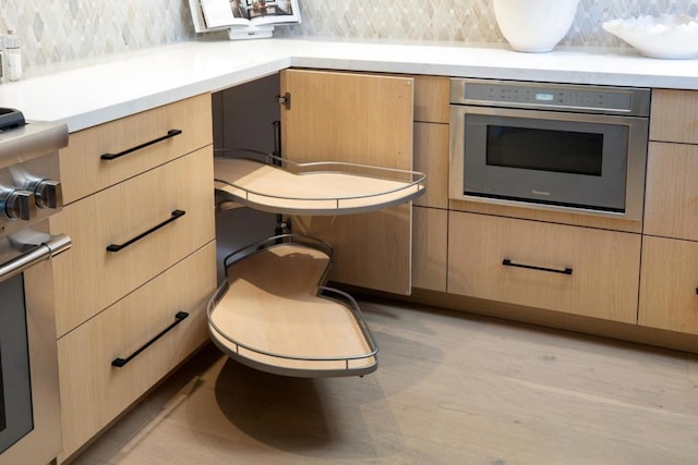 kitchen featuring light brown cabinetry, decorative backsplash, and oven