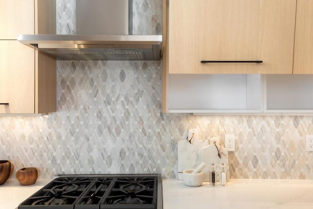 kitchen featuring light brown cabinets, light stone countertops, stove, range hood, and backsplash