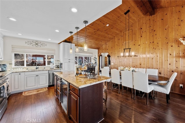 1430 Sequoia Dr, Lake Arrowhead, CA 92352 - kitchen with appliances with stainless steel finishes, white cabinets, a kitchen breakfast bar, wooden walls, and dark wood-type flooring
