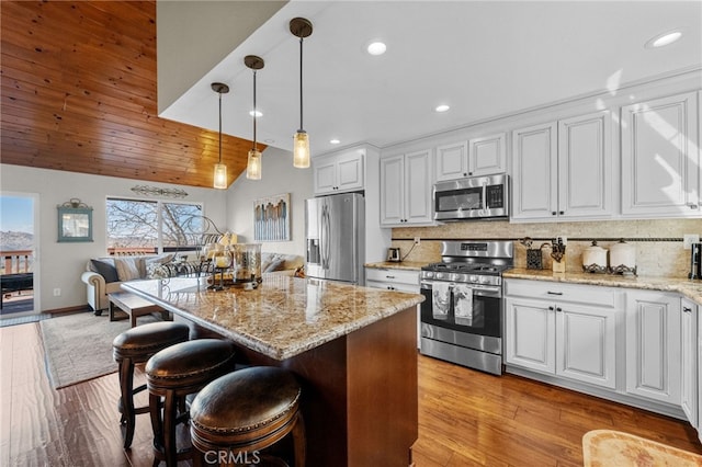 1430 Sequoia Dr, Lake Arrowhead, CA 92352 - kitchen featuring appliances with stainless steel finishes, white cabinets, open floor plan, backsplash, and decorative light fixtures