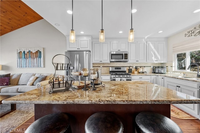 1430 Sequoia Dr, Lake Arrowhead, CA 92352 - kitchen featuring appliances with stainless steel finishes, a breakfast bar area, white cabinets, dark wood-type flooring, and vaulted ceiling