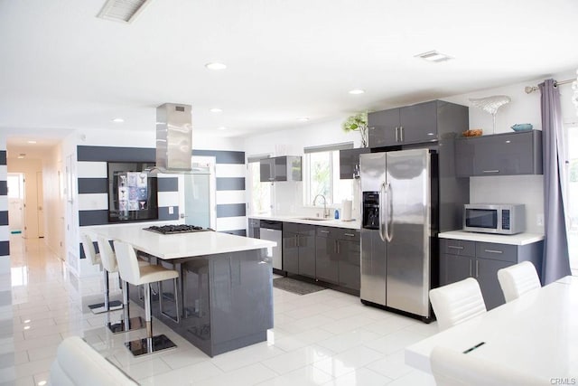 kitchen with a kitchen island, island range hood, sink, a breakfast bar area, and stainless steel appliances