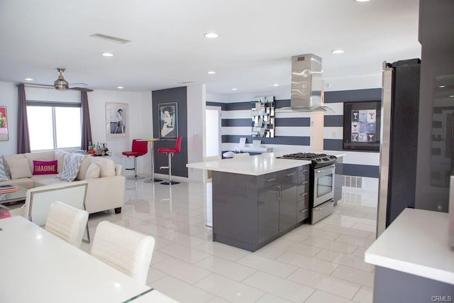 kitchen featuring island exhaust hood, a center island, light tile patterned floors, appliances with stainless steel finishes, and ceiling fan