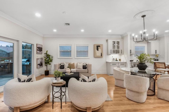 living room with crown molding, an inviting chandelier, and light hardwood / wood-style floors