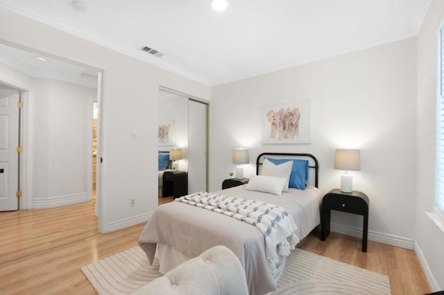 bedroom with light hardwood / wood-style flooring, ornamental molding, and a closet