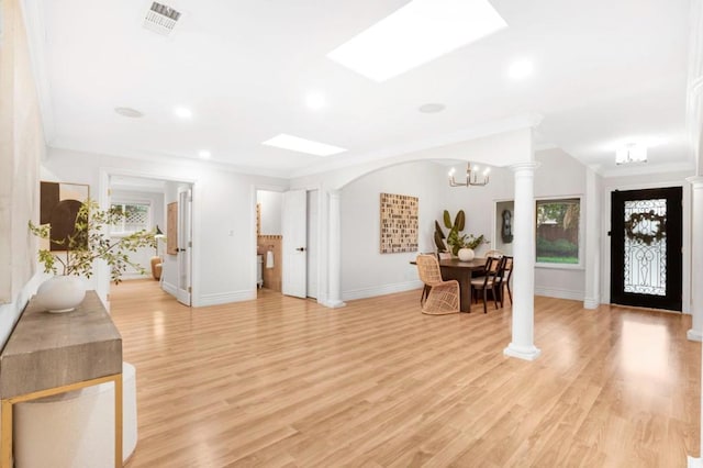 foyer featuring ornamental molding, light hardwood / wood-style floors, a chandelier, and ornate columns