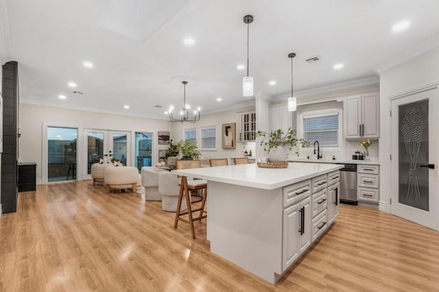 kitchen featuring sink, white cabinetry, hanging light fixtures, a kitchen breakfast bar, and a kitchen island