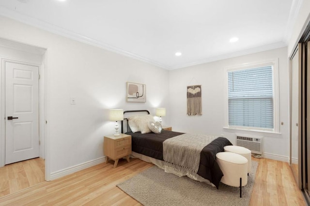 bedroom with ornamental molding, light hardwood / wood-style floors, a closet, and an AC wall unit