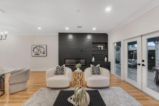 living room featuring hardwood / wood-style flooring, crown molding, a notable chandelier, and french doors