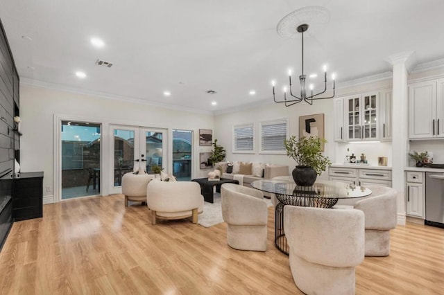 living room featuring light hardwood / wood-style flooring, ornamental molding, french doors, and a chandelier