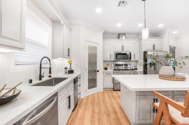 kitchen featuring white cabinetry, appliances with stainless steel finishes, sink, and hanging light fixtures