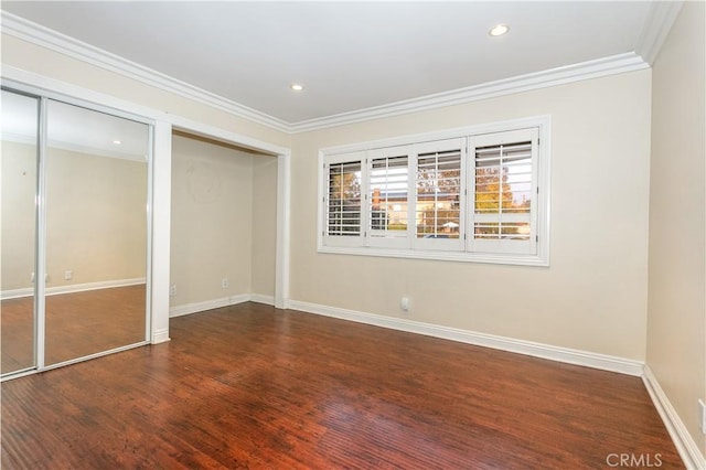 unfurnished bedroom with ornamental molding, wood-type flooring, and two closets