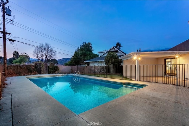 pool at dusk featuring a patio