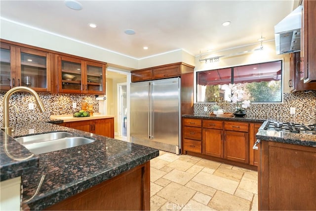 kitchen featuring stainless steel appliances, sink, decorative backsplash, and dark stone countertops