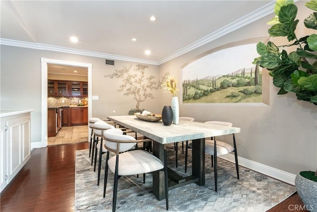 dining space with hardwood / wood-style floors and crown molding