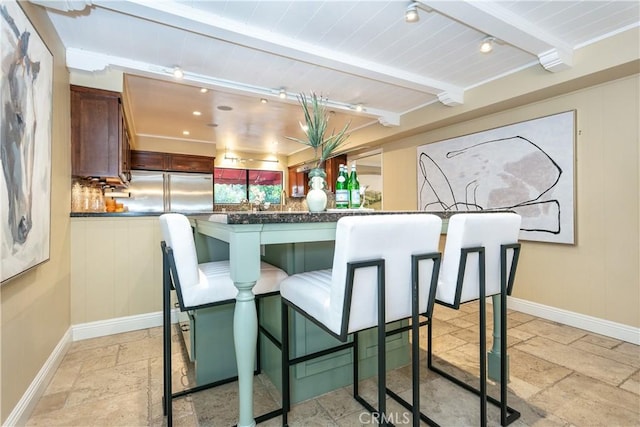 kitchen featuring a kitchen breakfast bar, kitchen peninsula, beamed ceiling, and built in refrigerator