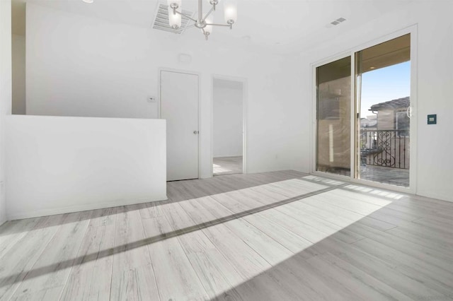 empty room featuring an inviting chandelier and light hardwood / wood-style flooring