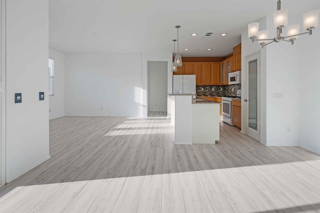 kitchen featuring decorative light fixtures, decorative backsplash, a notable chandelier, light hardwood / wood-style floors, and white appliances