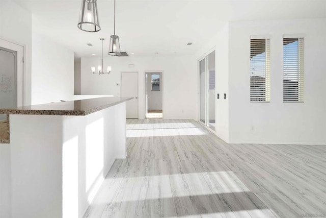 interior space with light hardwood / wood-style flooring, a notable chandelier, and decorative light fixtures