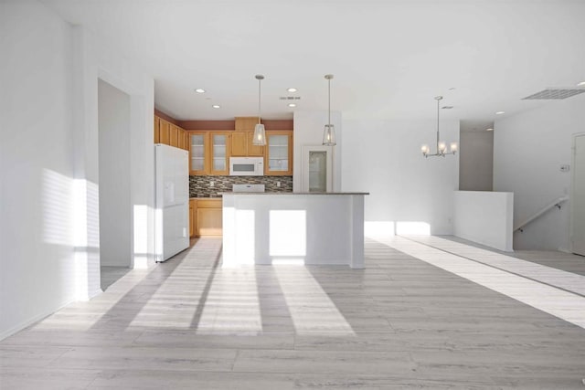 kitchen with tasteful backsplash, light hardwood / wood-style flooring, white appliances, and decorative light fixtures