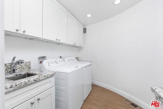 laundry area featuring cabinets, sink, washing machine and clothes dryer, and light wood-type flooring