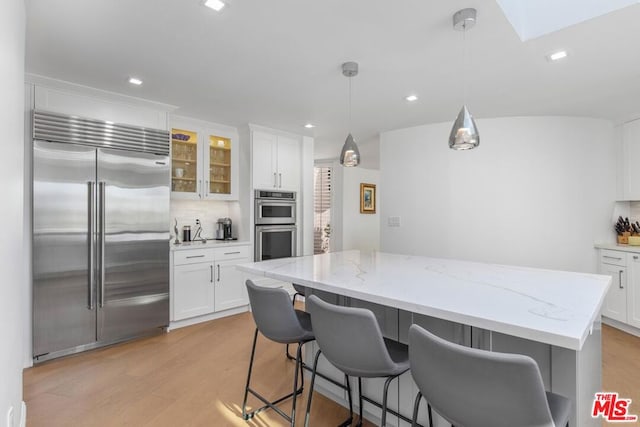 kitchen featuring stainless steel appliances, a breakfast bar area, hanging light fixtures, and white cabinets