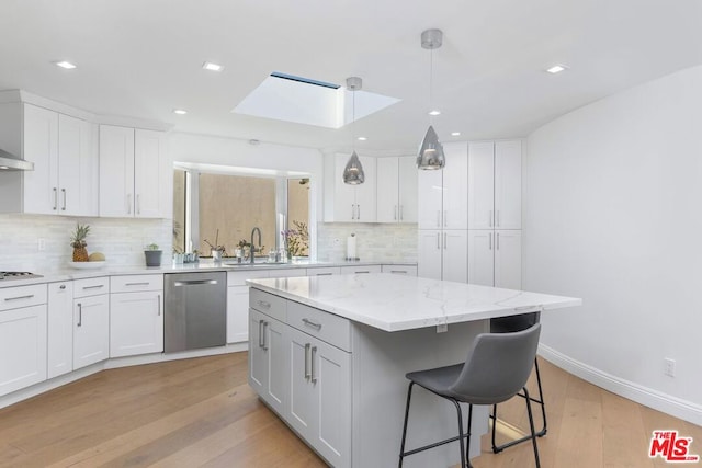 kitchen with white cabinetry, stainless steel dishwasher, and a kitchen island