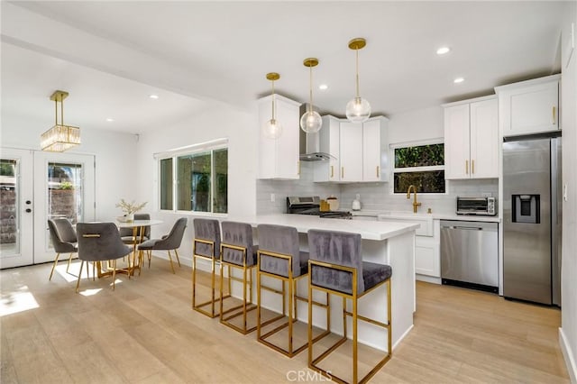 kitchen featuring white cabinetry, hanging light fixtures, stainless steel appliances, and a kitchen breakfast bar