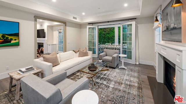 living room featuring crown molding, dark wood-type flooring, and a tray ceiling