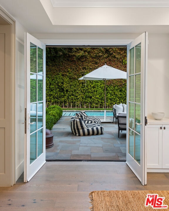 entryway featuring crown molding, french doors, and light wood-type flooring