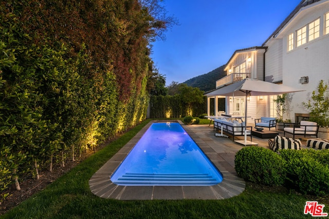 view of swimming pool featuring outdoor lounge area, a mountain view, and a patio