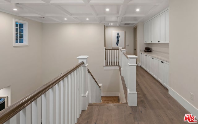 staircase featuring hardwood / wood-style flooring, coffered ceiling, and beamed ceiling