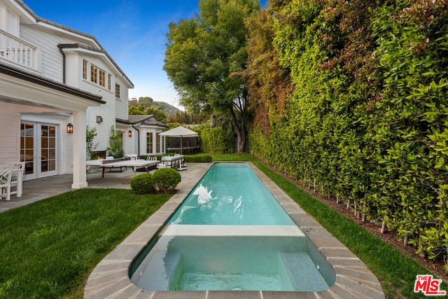 view of pool featuring a patio, a lawn, and french doors