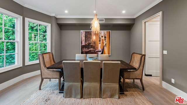 dining area featuring an inviting chandelier, crown molding, and light wood-type flooring