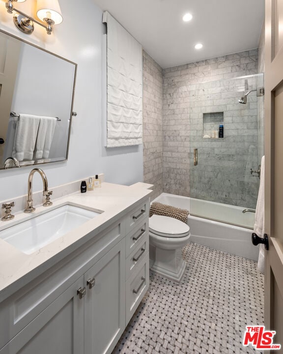 full bathroom featuring vanity, toilet, and combined bath / shower with glass door