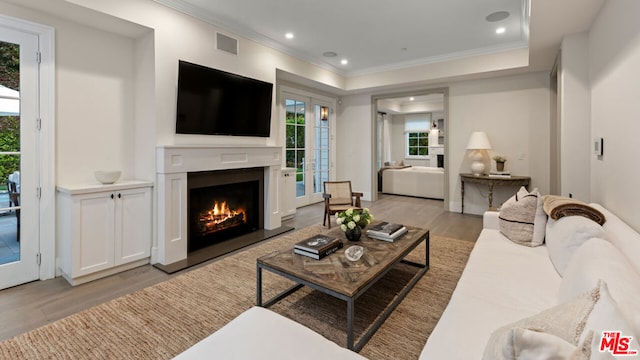 living room featuring crown molding and light hardwood / wood-style flooring