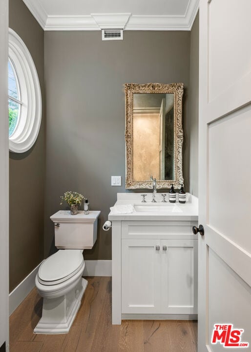 bathroom with crown molding, vanity, toilet, and hardwood / wood-style floors