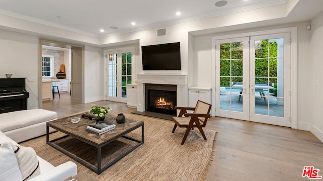 living room featuring french doors, crown molding, and light hardwood / wood-style flooring