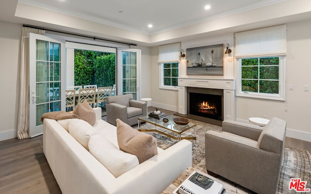 living room featuring wood-type flooring, ornamental molding, and plenty of natural light