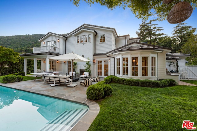 rear view of house featuring a balcony, a yard, an outdoor hangout area, and a patio area