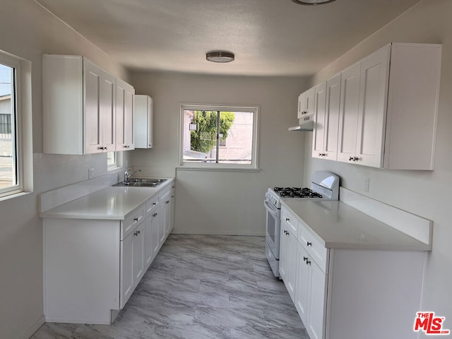 kitchen with sink, white range with gas stovetop, and white cabinets