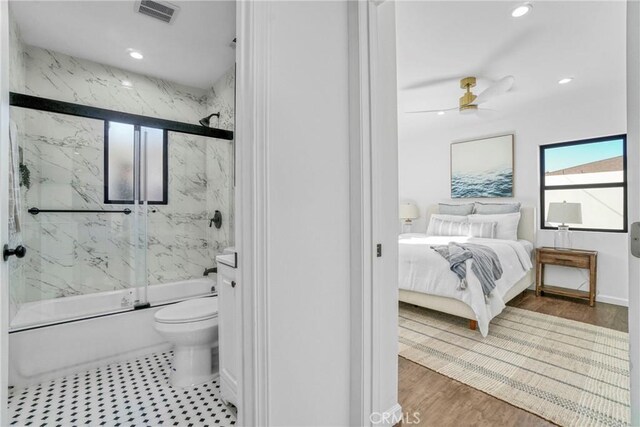 bathroom featuring ceiling fan, wood-type flooring, toilet, and combined bath / shower with glass door