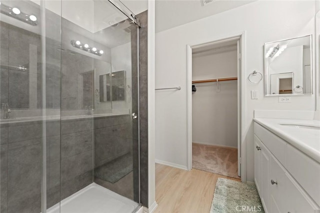 bathroom with wood-type flooring, a shower with door, and vanity