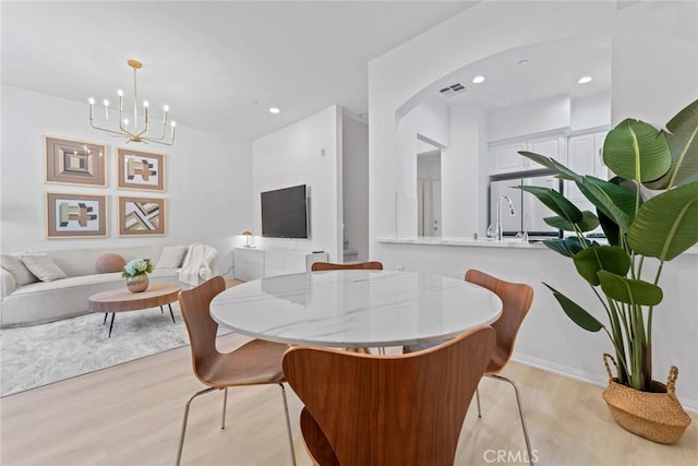 dining room with a notable chandelier, light hardwood / wood-style flooring, and sink