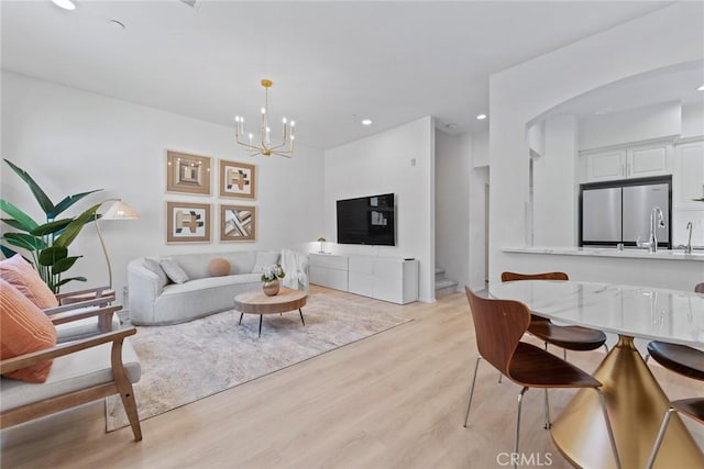 living room with sink, an inviting chandelier, and light wood-type flooring