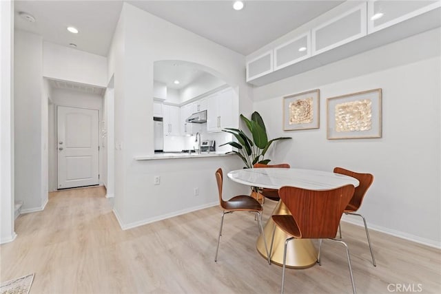 dining space with sink and light wood-type flooring