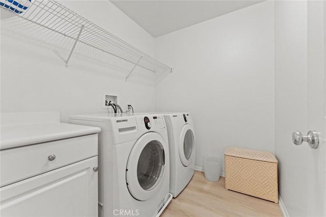 laundry area with separate washer and dryer and light hardwood / wood-style flooring