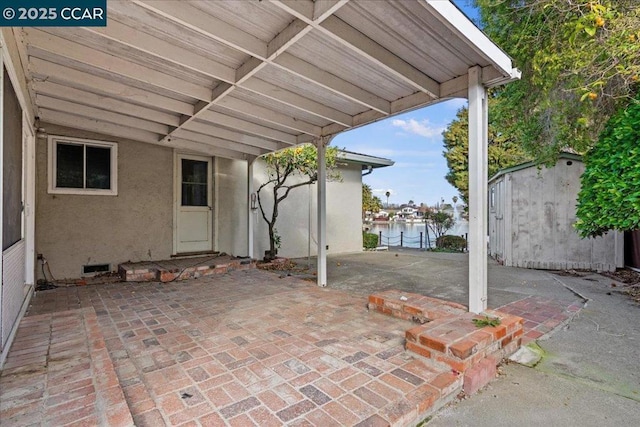 view of patio / terrace with a water view and a storage shed