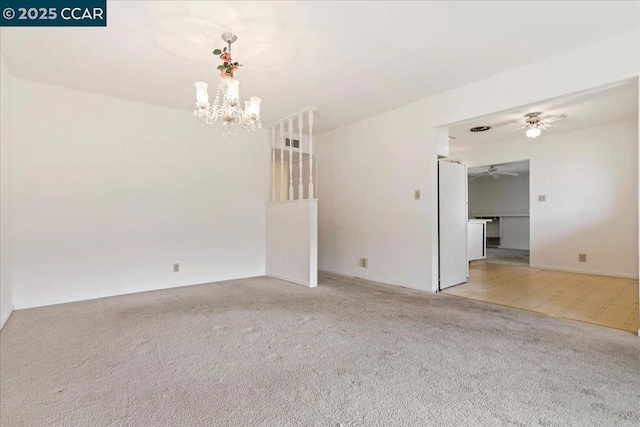 empty room with ceiling fan with notable chandelier and light colored carpet